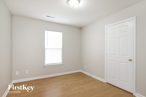 a bedroom with white walls and a wooden floor and a white door
