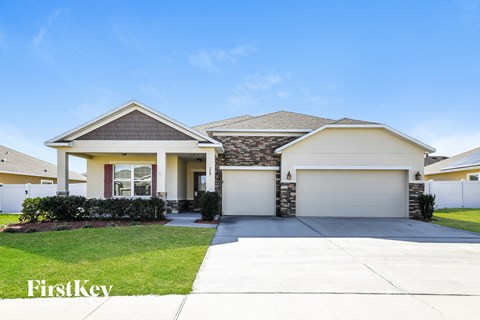a beige house with a garage door and a lawn