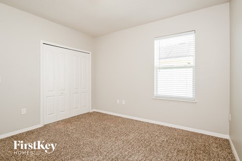 a bedroom with carpet and a white door and window