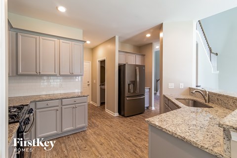 A kitchen with a granite counter top and wooden floors.