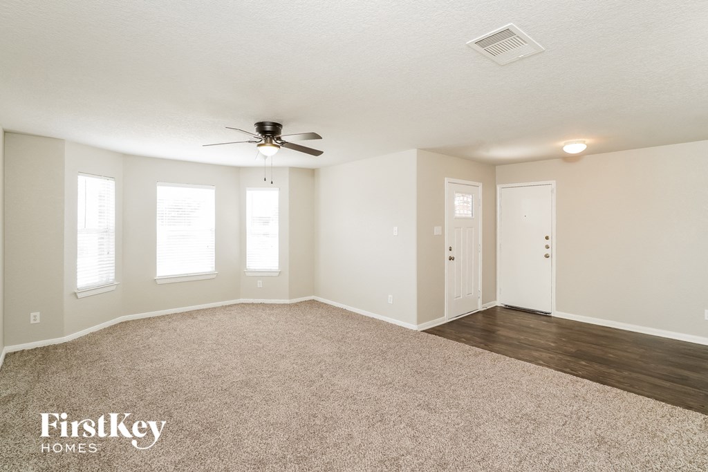 the living room of an empty house with a ceiling fan