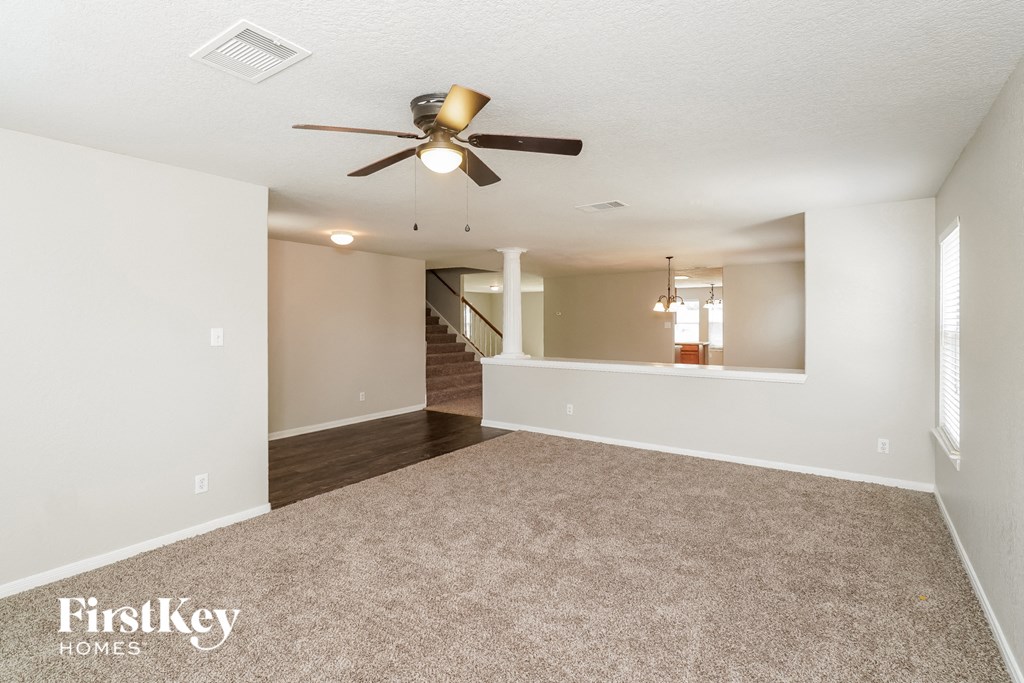 an empty living room with a ceiling fan