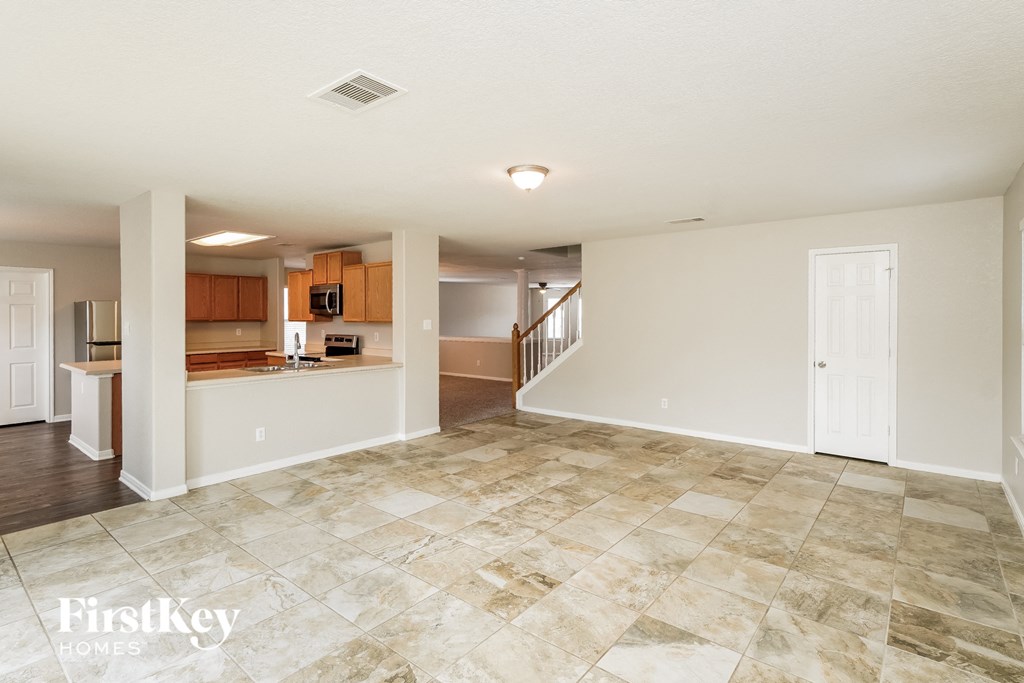 an empty living room with a kitchen and a staircase