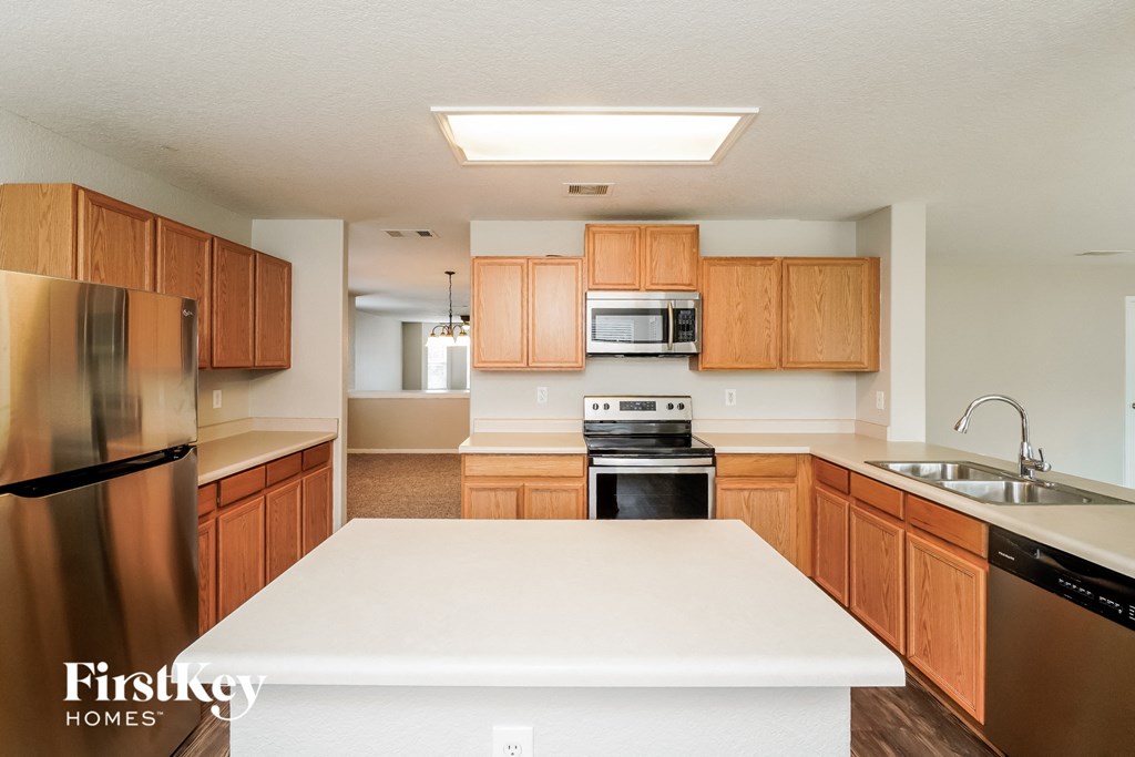 an empty kitchen with wooden cabinets and a white counter top