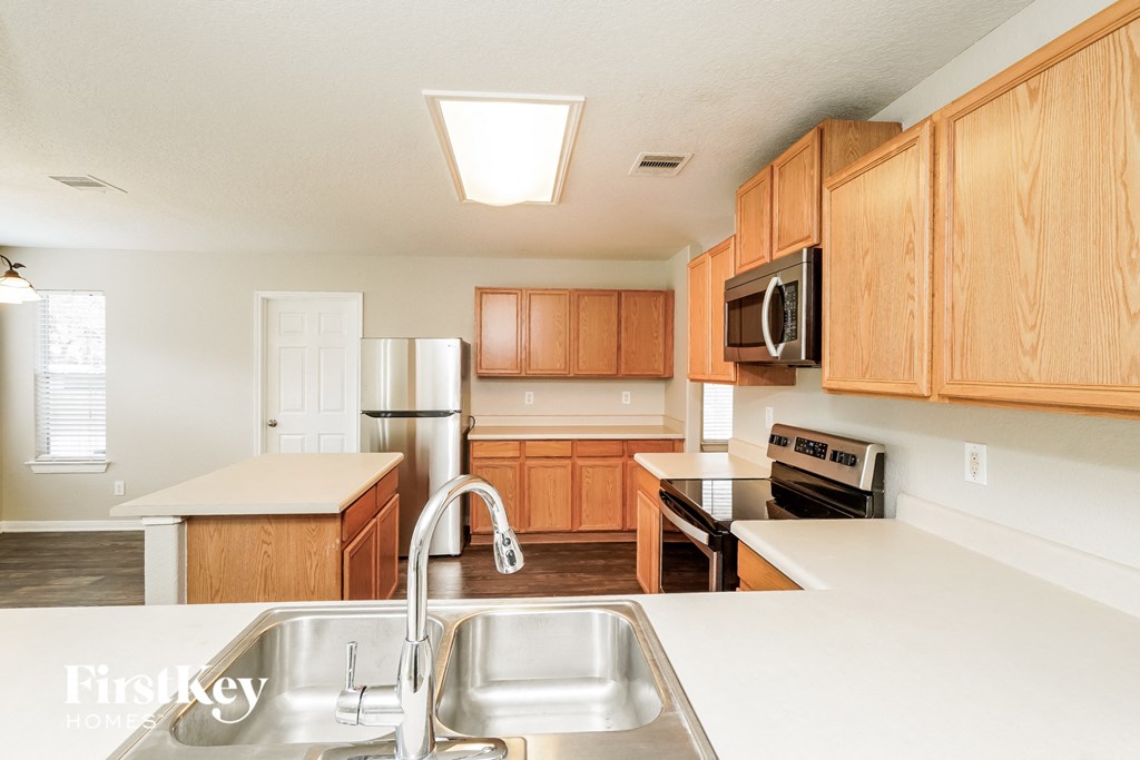 a kitchen with wooden cabinets and white counter tops and a sink