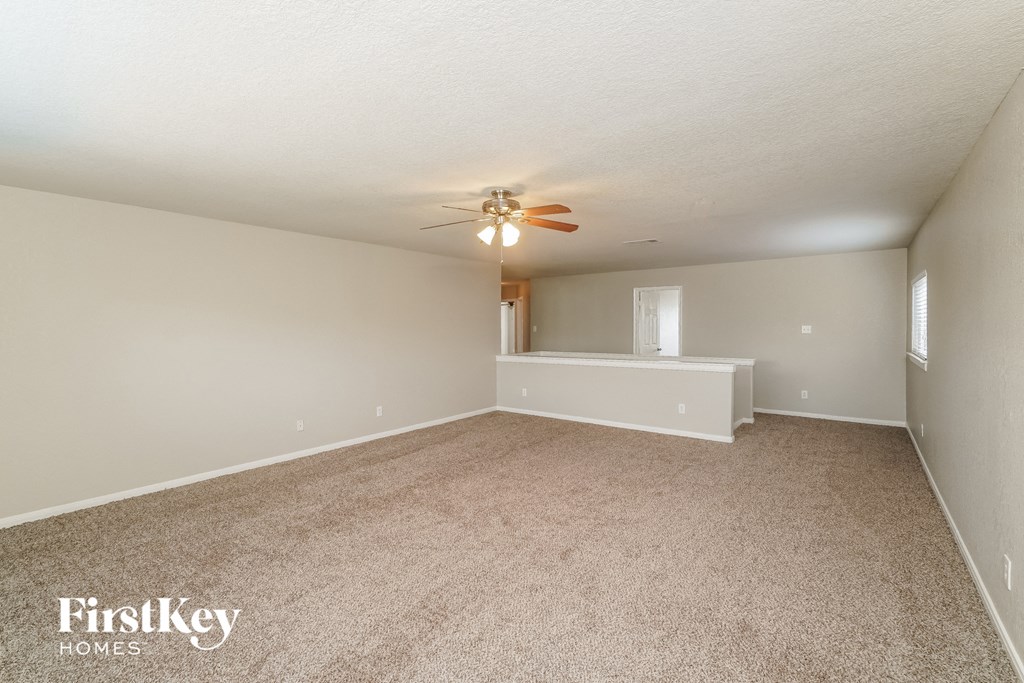 a spacious living room with carpet and a ceiling fan