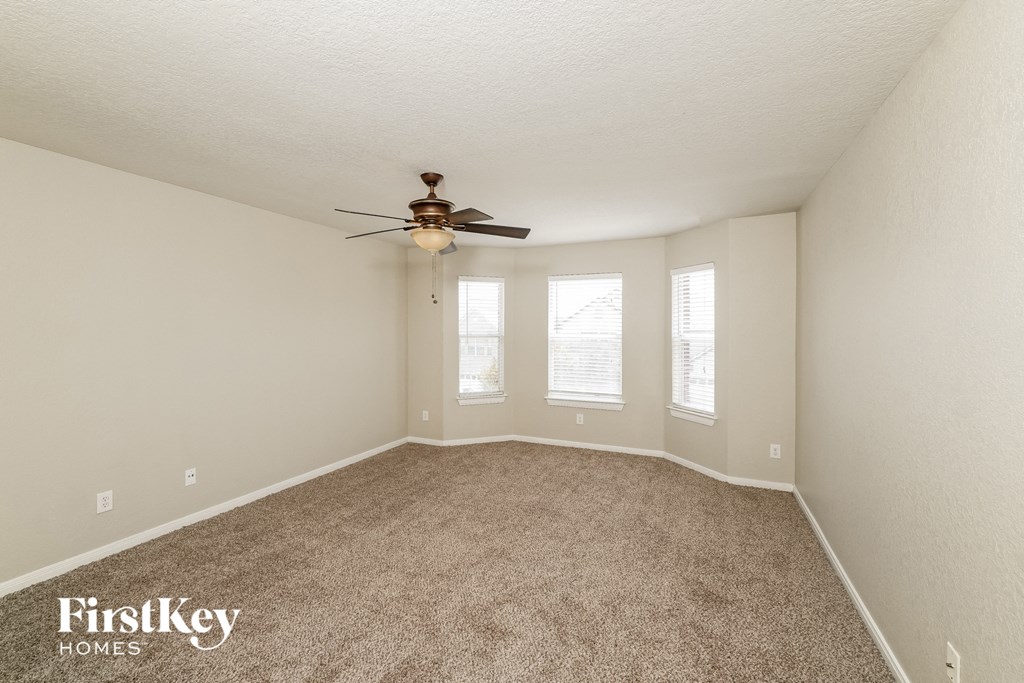 an empty room with a ceiling fan and three windows