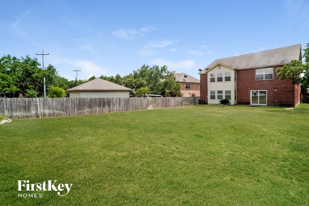 the backyard of a brick house with a yard and a wooden fence