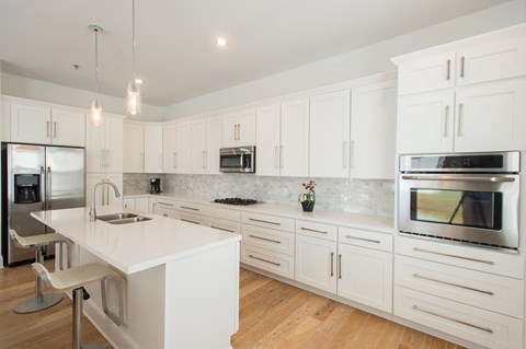 a large white kitchen with white cabinets and stainless steel appliances