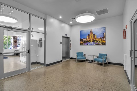 a lobby with two chairs and a table and a painting on the wall