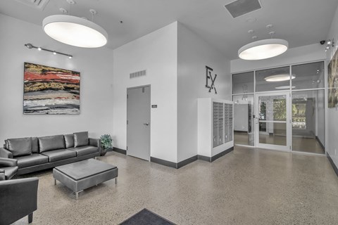 the lobby of a building with white walls and leather furniture