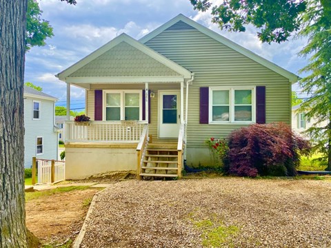 A small house with a front porch and a gravel driveway.
