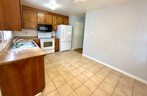 A kitchen with a white refrigerator and wooden cabinets.