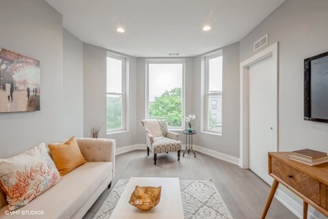 A living room with a white sofa and a chair with a floral pattern.