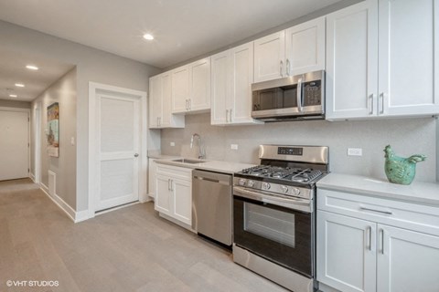A modern kitchen with white cabinets and stainless steel appliances.