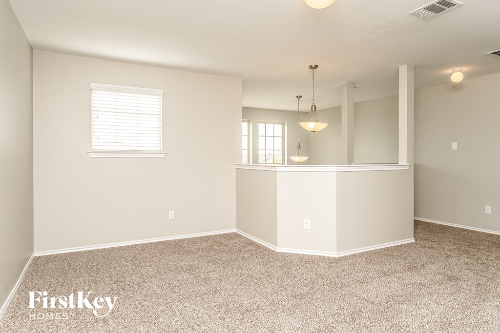 the kitchen and living room of a renovated home with carpeting and a bar