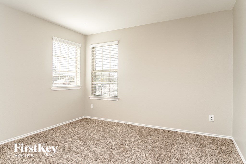 a empty room with carpet and two windows
