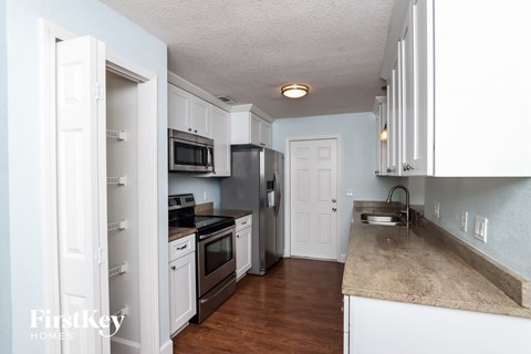 A kitchen with white cabinets and a granite counter top.