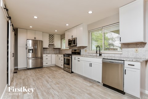 A modern kitchen with white cabinets and stainless steel appliances.