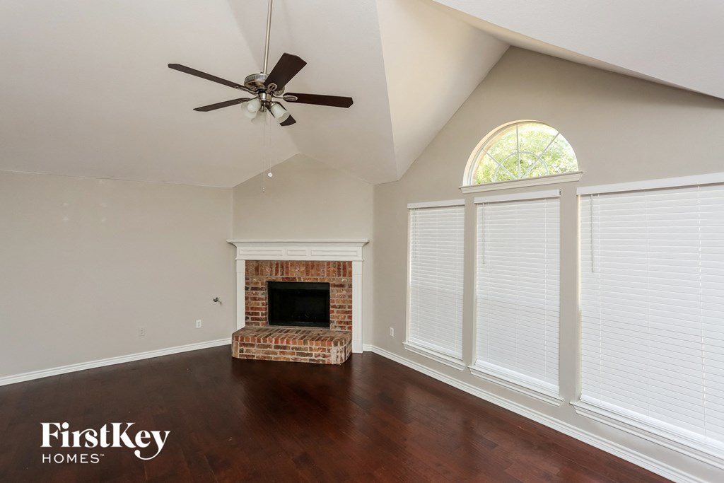 a living room with a brick fireplace and a ceiling fan