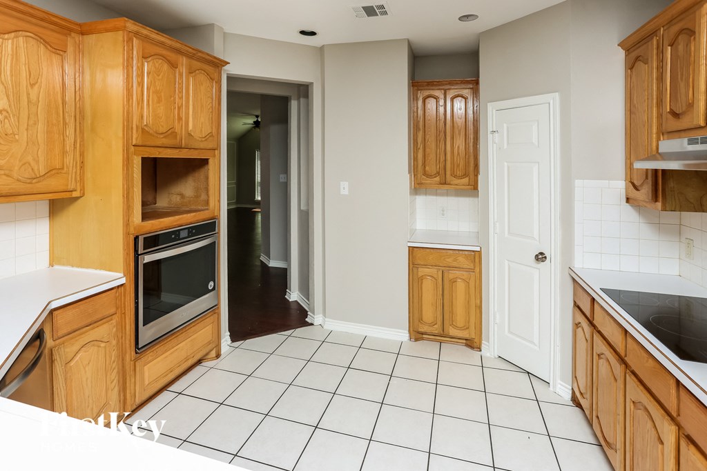 a kitchen with wooden cabinets and a white tile floor