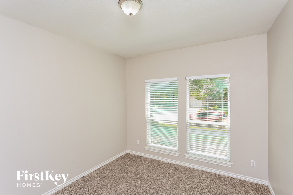 a bedroom with two windows and a carpeted floor