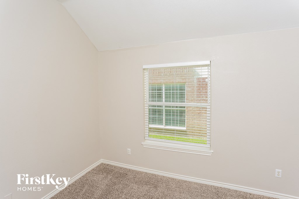 a bedroom with a window and a carpeted floor