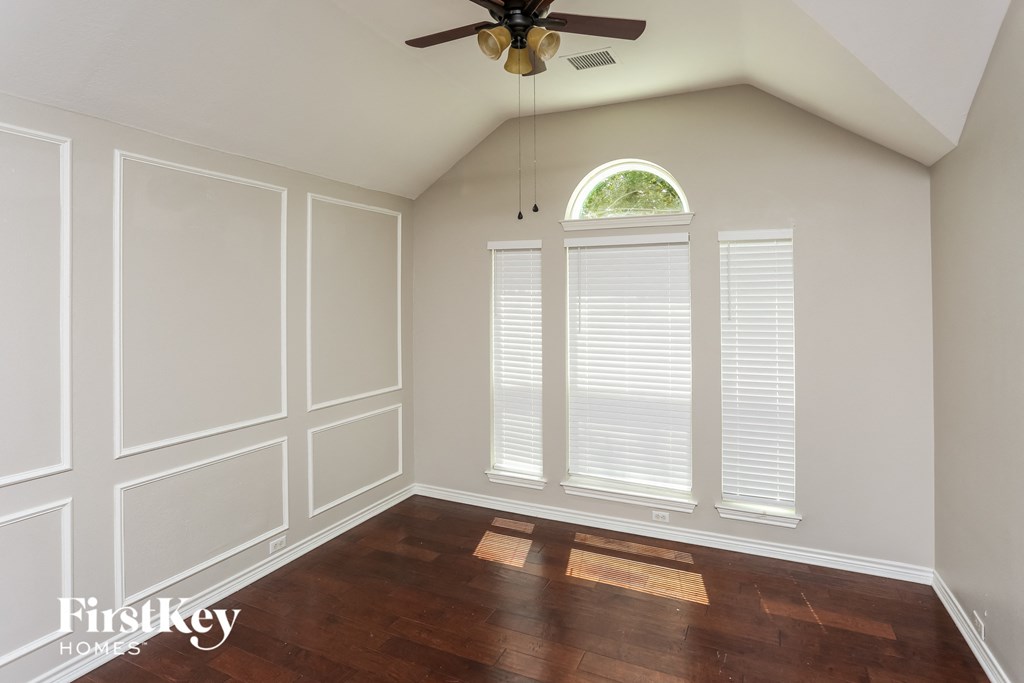 a living room with white walls and a window and a ceiling fan
