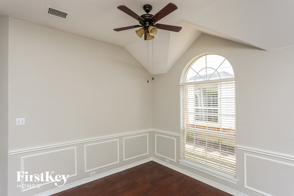 a bedroom with a large window and a ceiling fan