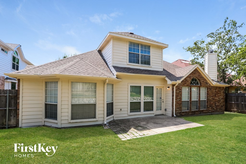the front of a yellow house with a yard and grass
