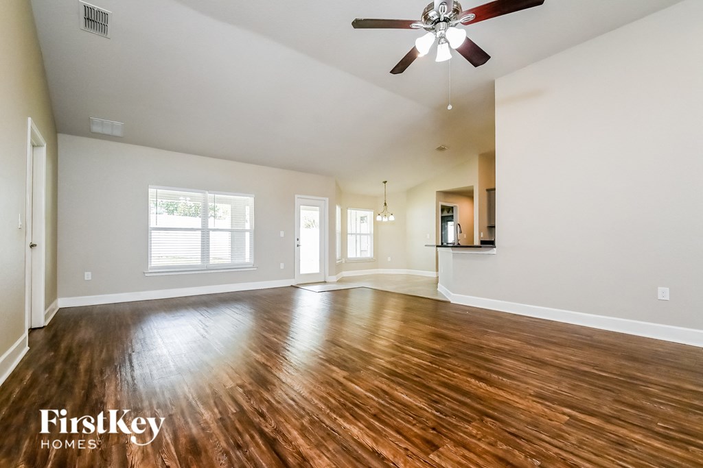 A spacious room with wooden floors and a ceiling fan.