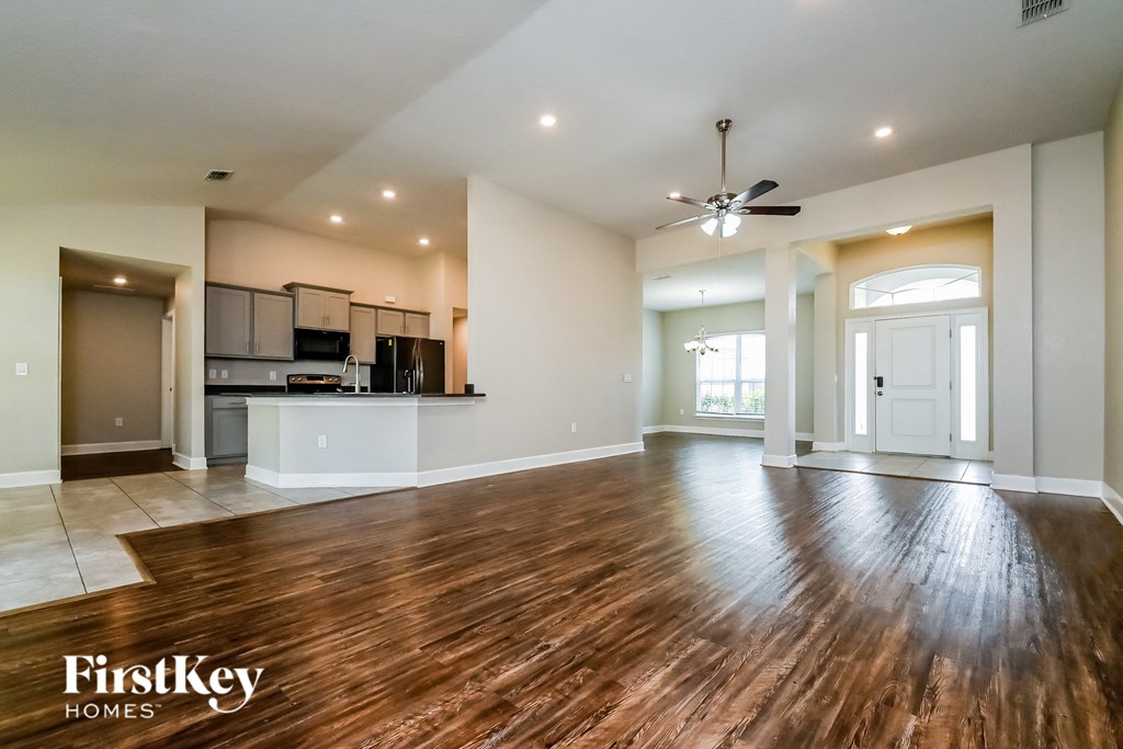 A spacious living room with wooden floors and a ceiling fan.