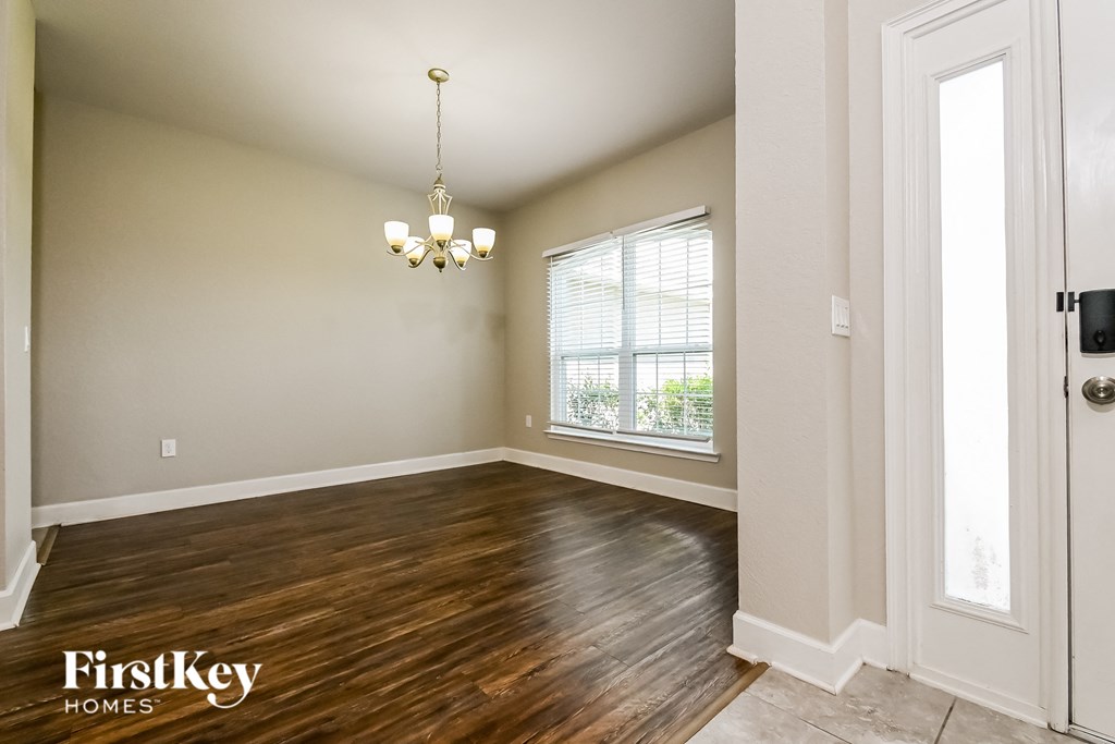 A room with wooden floors and a chandelier hanging from the ceiling.