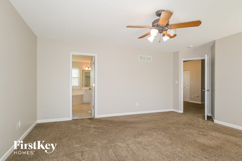 a living room with a ceiling fan and a carpet