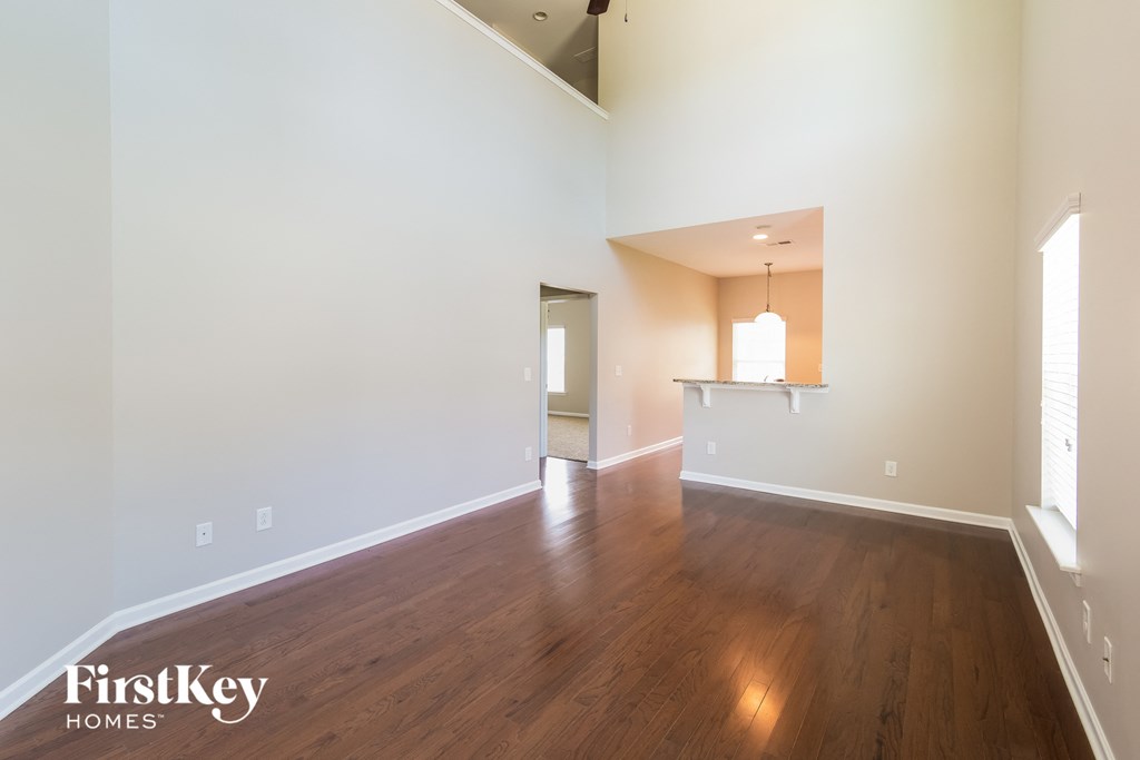 an empty living room with wood floors and white walls