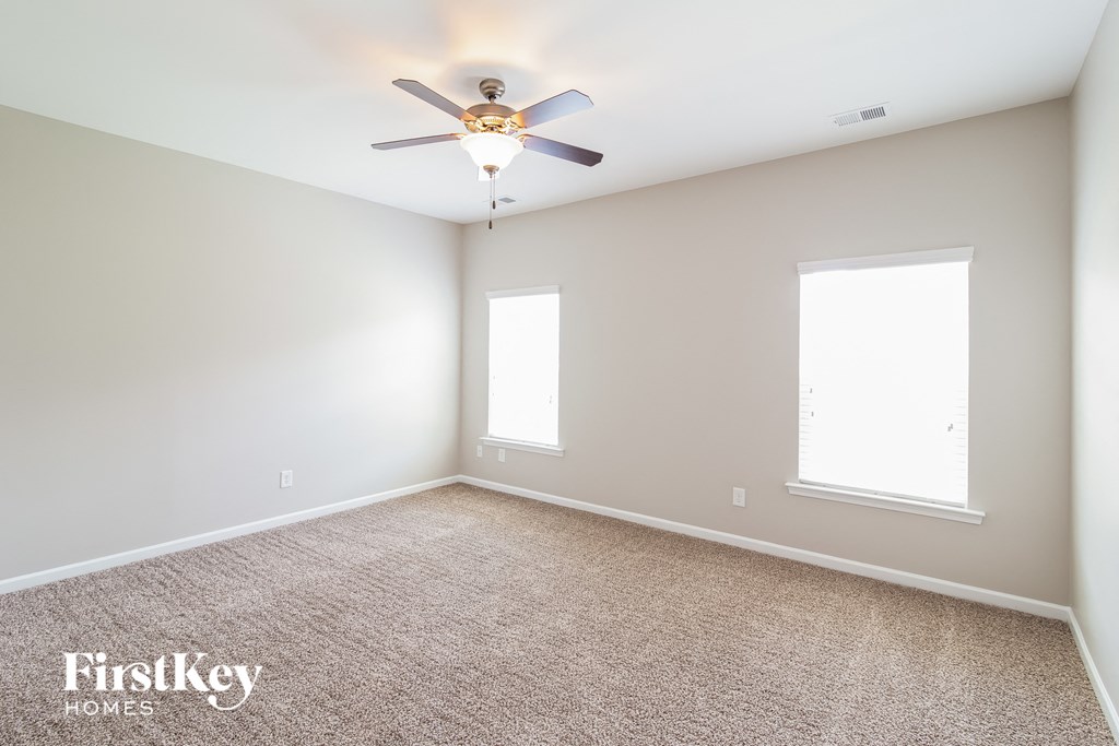 an empty room with a ceiling fan and two windows