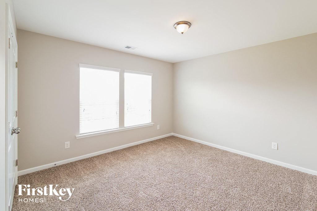 a empty room with carpet and two windows