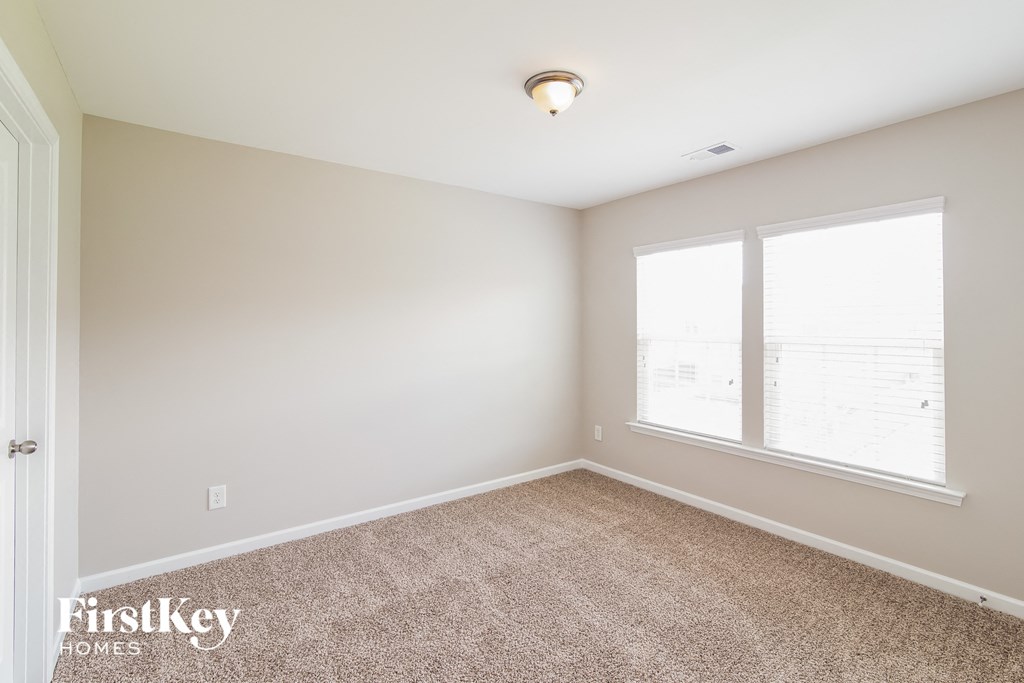 a bedroom with a carpeted floor and two windows