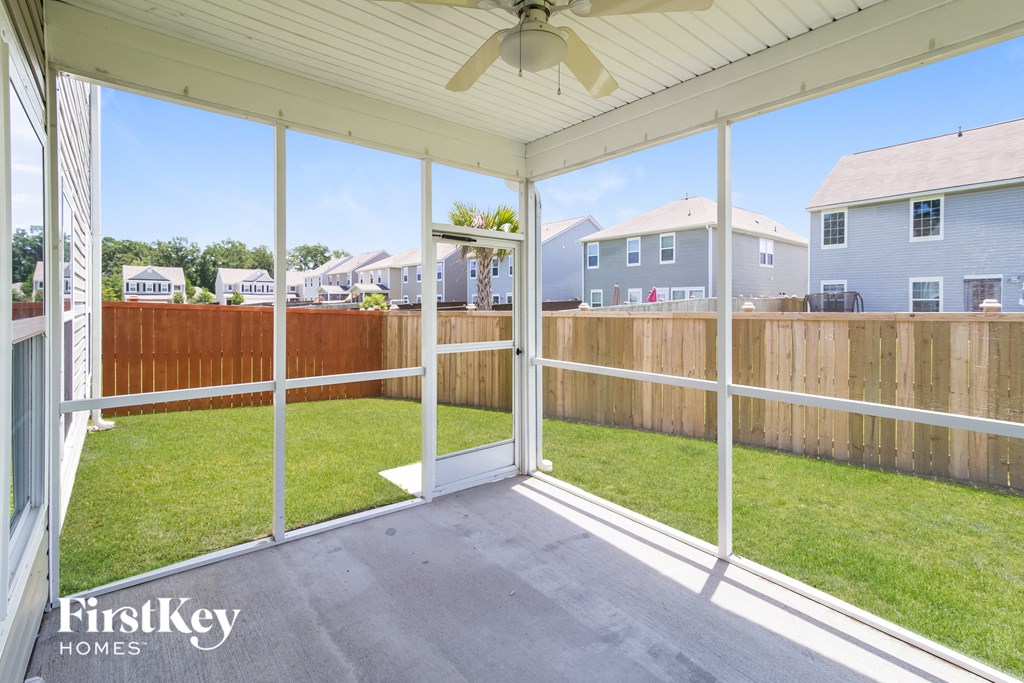 the screened porch of a home with a lawn and a fence