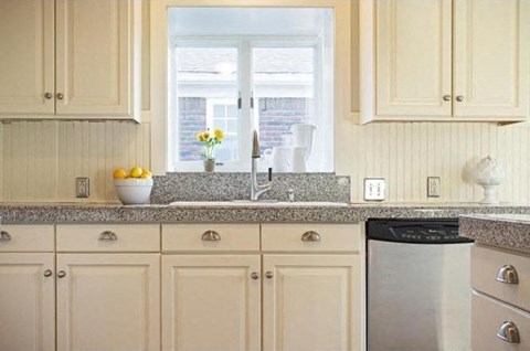 a kitchen with white cabinets and a sink and a window