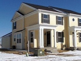 A yellow house with a black roof and white trim.