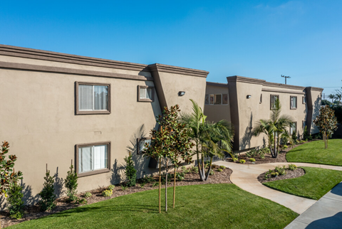a group of apartments with a walkway and grass and trees