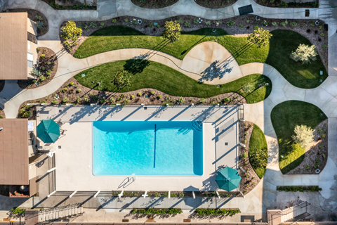 an aerial view of a swimming pool in a backyard with a lawn and a lawn
