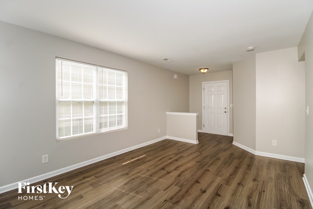 the living room of a home with wood flooring and a white door