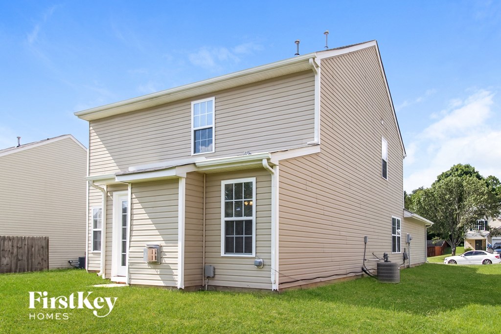 a small house with beige siding on a green lawn