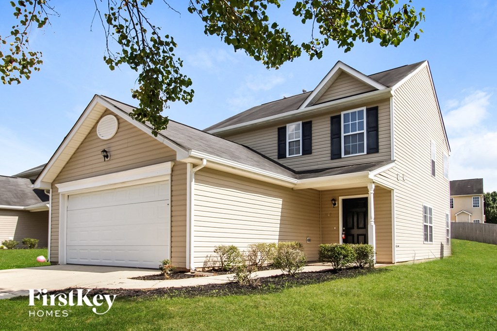 a yellow house with a garage and a lawn