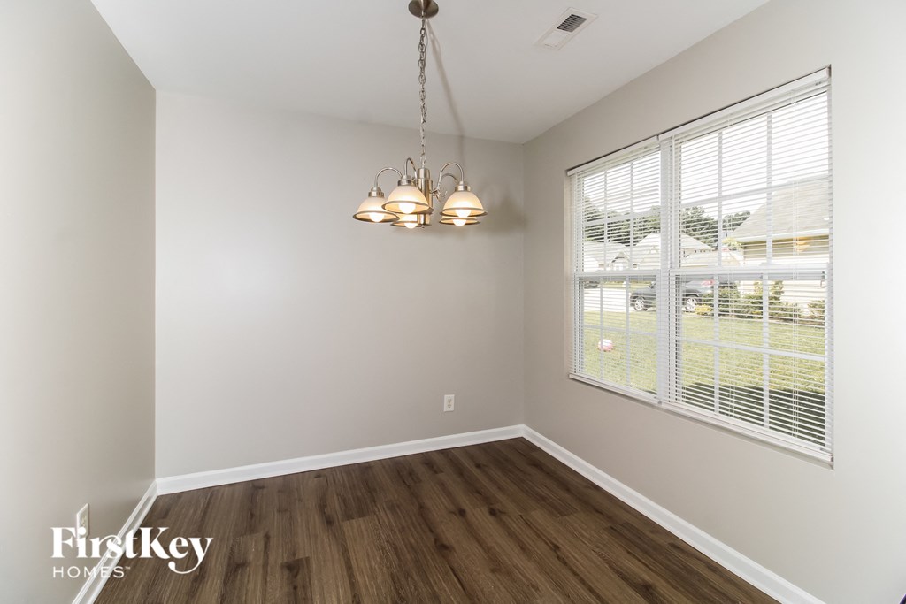 a living room with a large window and wooden floors and a chandelier