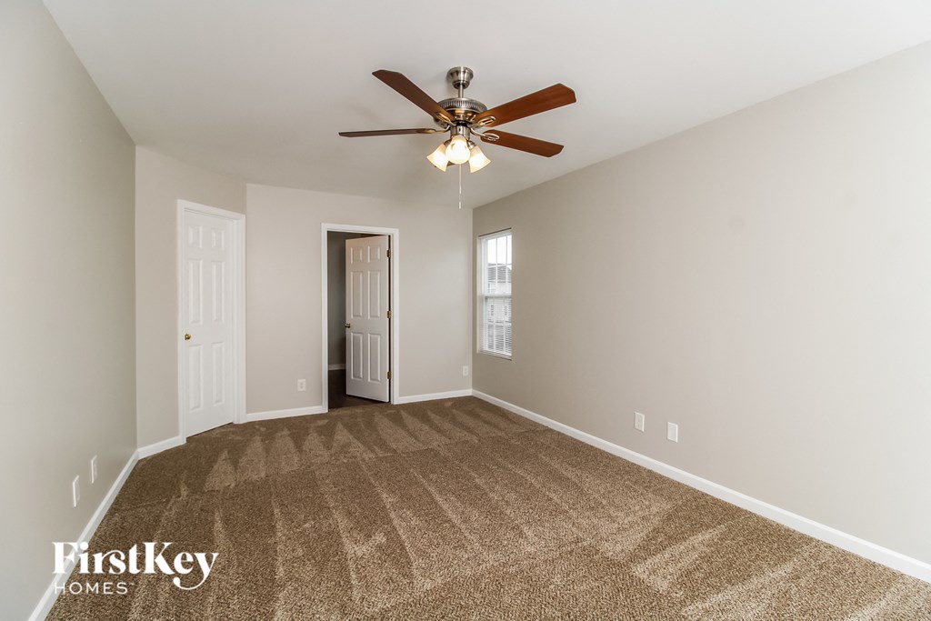 a spacious living room with carpet and a ceiling fan