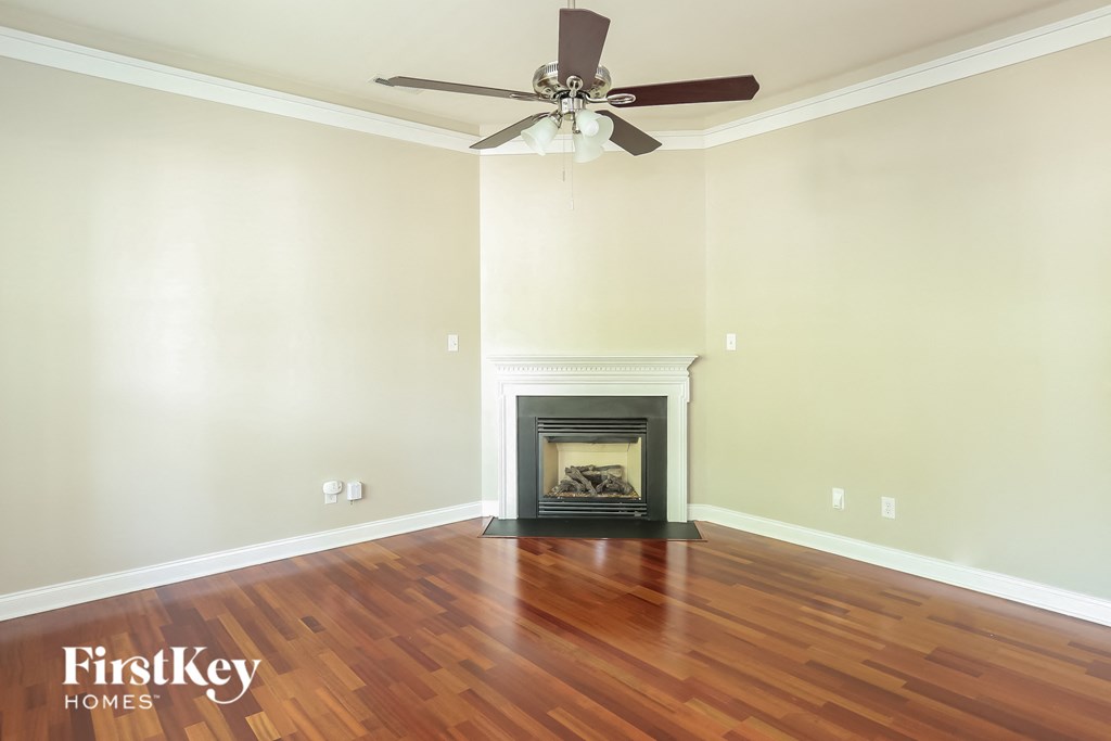 a living room with wood floors and a fireplace and a ceiling fan