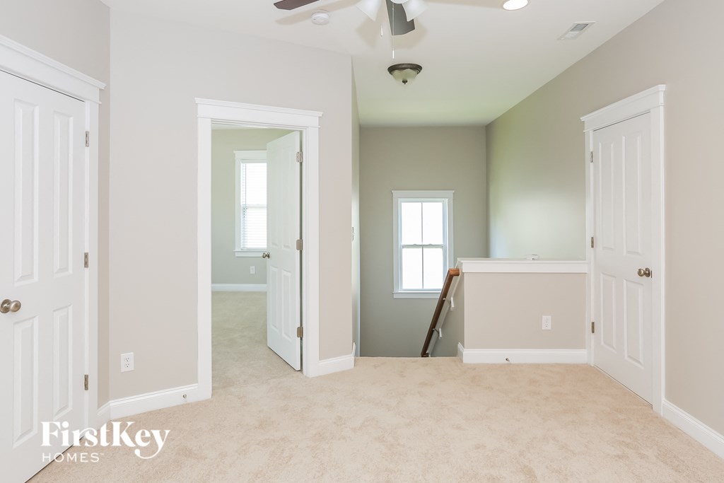 an empty living room with a white carpet and a white door open to a hallway